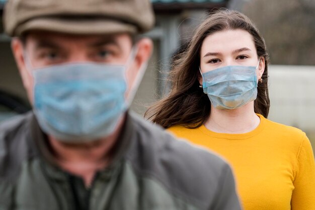 Photo teen girl and her father in medical masks outdoors