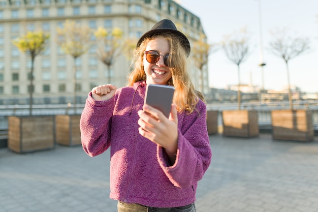 Teen girl hipster in hat and glasses with mobile phone