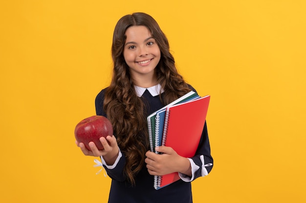 Teen girl hold apple after study healthy childhood happy kid going to do homework teenager student hold copybooks education in high school schoolgirl with apple lunch back to school