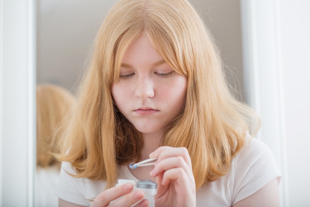 Teen girl holds blue eye lens