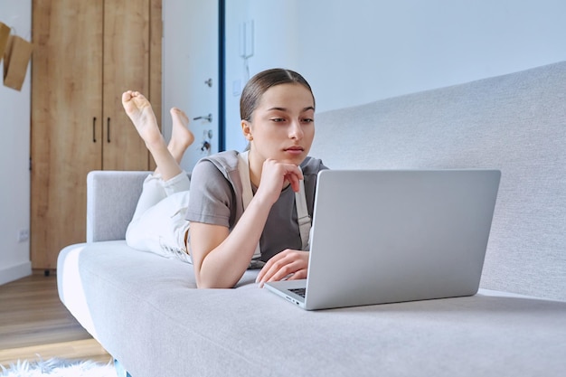 teen girl at home on couch using laptop