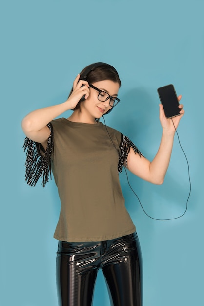 Девушка-подросток слушает музыку на своем мобильном телефоне с наушниками