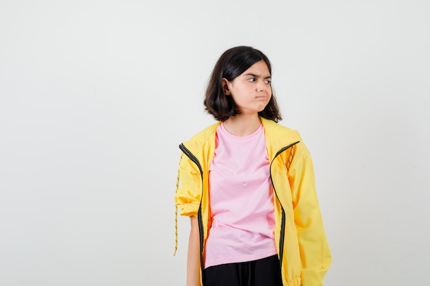 Teen girl looking aside in t-shirt, jacket and looking hesitant , front view.