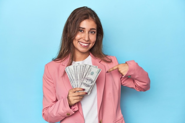 분홍색 옷을 입은 십대 소녀가 한 손의 달러 지폐를 과시하고 손으로 셔츠 복사 공간을 가리키는 사람