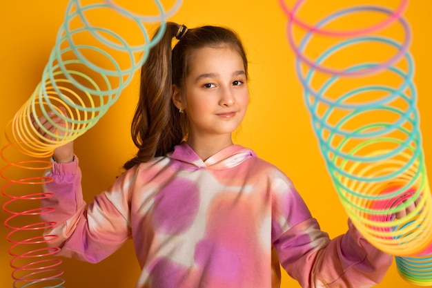 Photo teen girl play rainbow slinky toy on color background