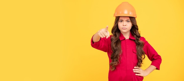 Teen girl pointing finger child in protective helmet for\
building protection and safety child builder in helmet horizontal\
poster design banner header copy space