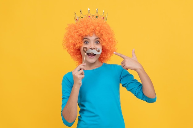 Teen girl pointing finger on moustache being a clown april fools day happy childhood girls birthday party happy funny kid in wig and crown imagine herself queen cheerful child wear diadem