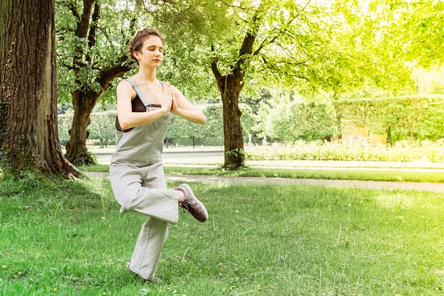 Девушка-подросток занимается йогой в парке YogaNatarajasanaLord of Dance балансирует на одной ноге