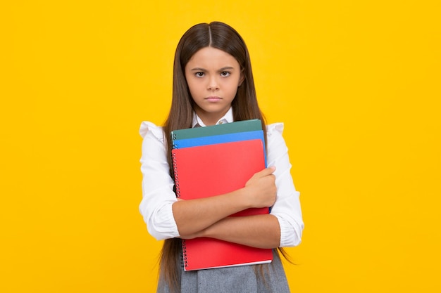 Teen girl pupil hold books notebooks isolated on yellow background copy space Back to school teenage lifestyle education and knowledge Angry schoolgirl upset and unhappy negative emotion