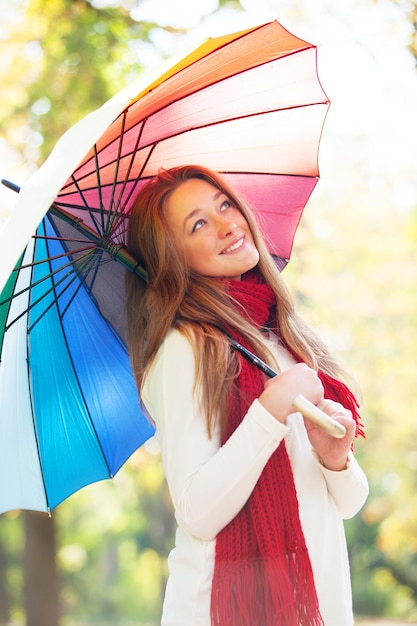 Teen girl in red scarf with umbrella at autumn outdoor