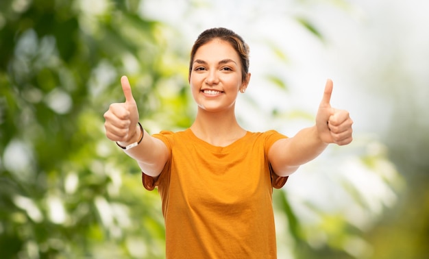 Photo teen girl showing thumbs up over natural backgdrop