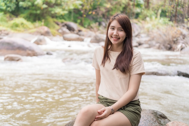 Teen girl sitting  near waterfall