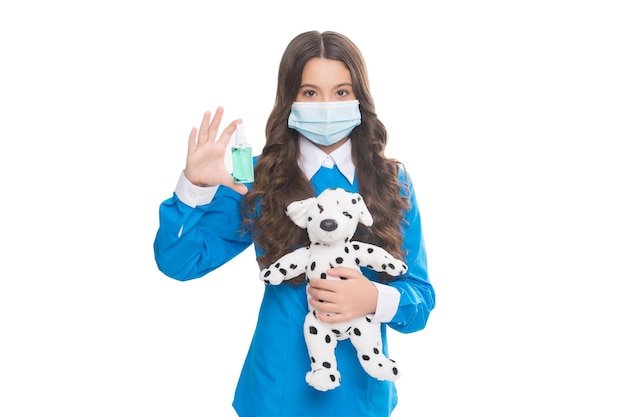 보호 마스크를 쓴 10대 소녀는 흰색, 바이러스 전염병에 격리된 소독제 젤과 개 장난감을 들고 있습니다.