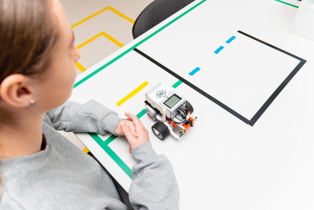Teen girl student with diy robot on stem education classTeen scientist working on new projectStem education Learning To Program Robot Vehicle