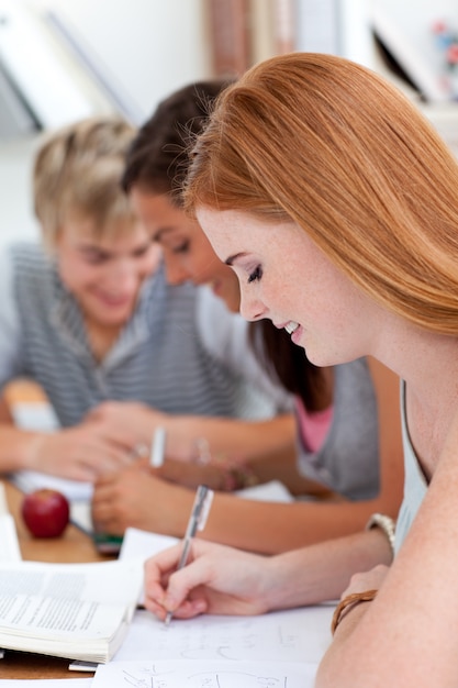 Foto ragazza teen studiando in biblioteca con i suoi amici