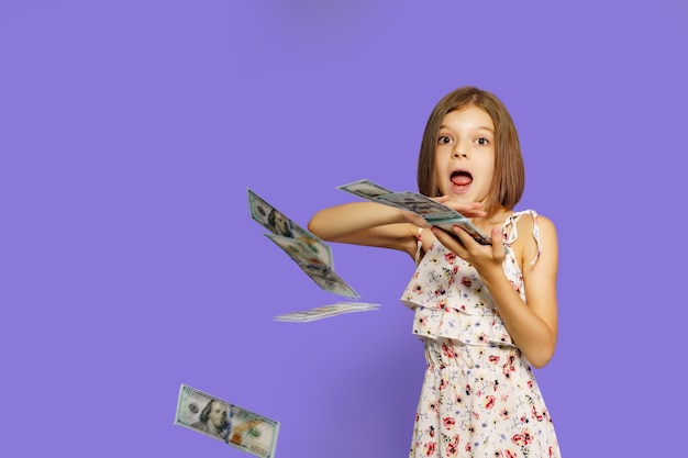 Teen girl in summer dress standing isolated with us dollar money banknotes over velvet