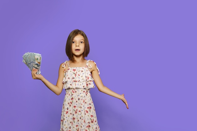 Teen girl in summer dress standing isolated with us dollar money banknotes over velvet