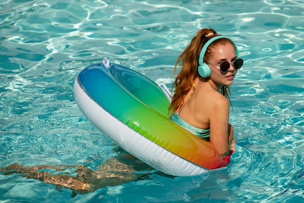 Teen girl in swimming pool playing in water vacation and traveling young woman with floating ring in...