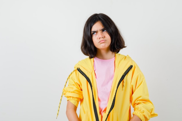 Teen girl in t-shirt, jacket posing while looking aside and looking angry , front view.