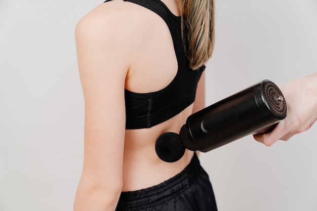 Teen girl uses massage gun.