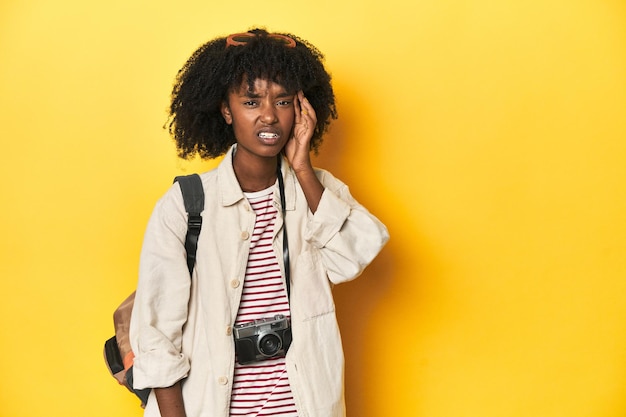 Teen girl with backpack camera ready for vacation showing a disappointment gesture with forefinger