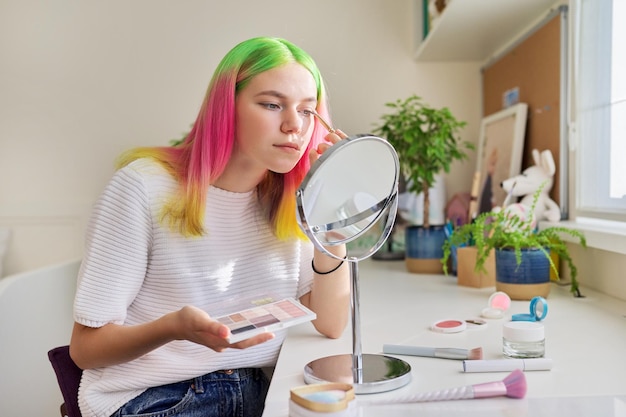 Foto ragazza teenager con i capelli tinti colorati che colorano i suoi occhi con le ombre decorative