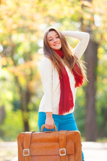 Teen girl with suitcase at autumn outdoor