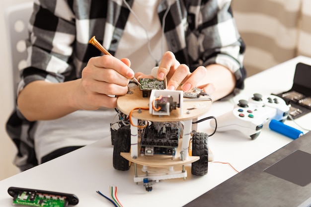 Teen hands programming and building science robotics project on his laptop at home during covid-19 pandemic lockdown