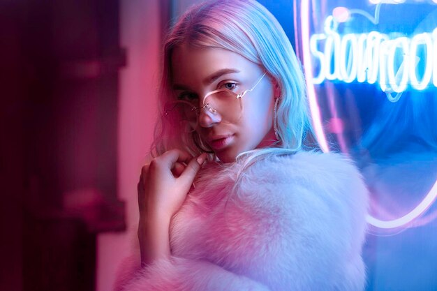 Teen hipster girl posing near neon sign on street portrait