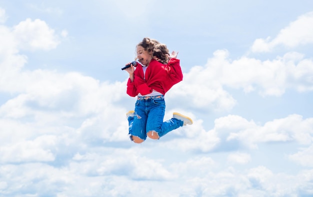 Teen kid jumping and singing with microphone in karaoke child singing outdoor singer with microphone happy childhood happy girl enjoy the moment Have Fun on Celebration
