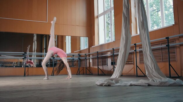Фото Юная модель молодая девушка изящно выполняет акробатические трюки в бальном зале, артист цирка