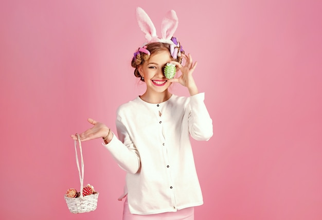 Photo teen paint eggs. easter little girl in bunny ears.