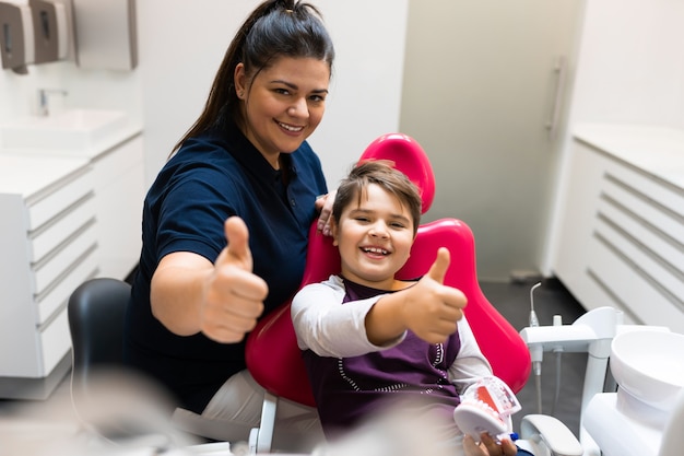 Teen patient and dentist show thumbs up