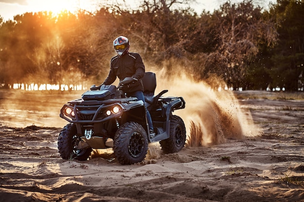 Teen riding ATV in sand dunes making a turn in the sand