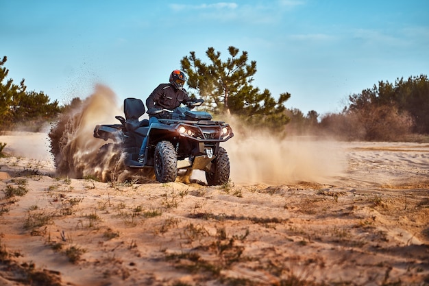 Teen riding ATV in sand dunes making a turn in the sand