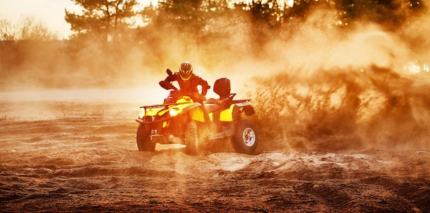 Teen riding ATV in sand dunes making a turn in the sand