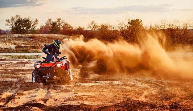 Teen riding ATV in sand dunes making a turn in the sand