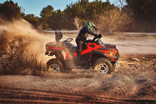 Foto adolescente che guida l'atv nelle dune di sabbia che fa un giro nella sabbia