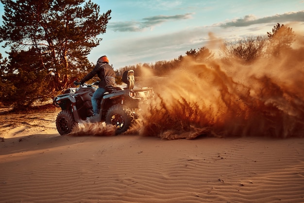 Teen riding ATV in sand dunes making a turn in the sand