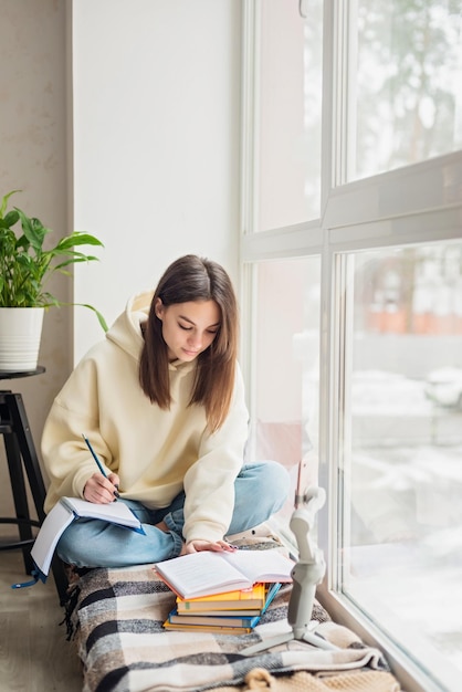 Teen school girl distant school or college student virtual\
remote e learning using mobile phone app in bedroom distance\
education classes studying online at home concept soft selective\
focus