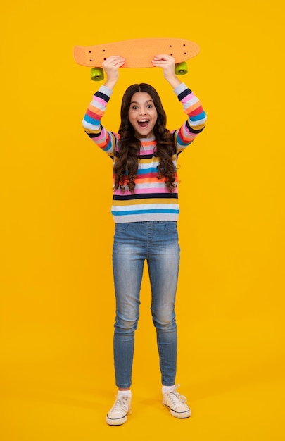 Teen school girl with skateboard on studio isolated background Schoolgirl trend urban teenager style Happy teenager positive and smiling emotions of teen girl