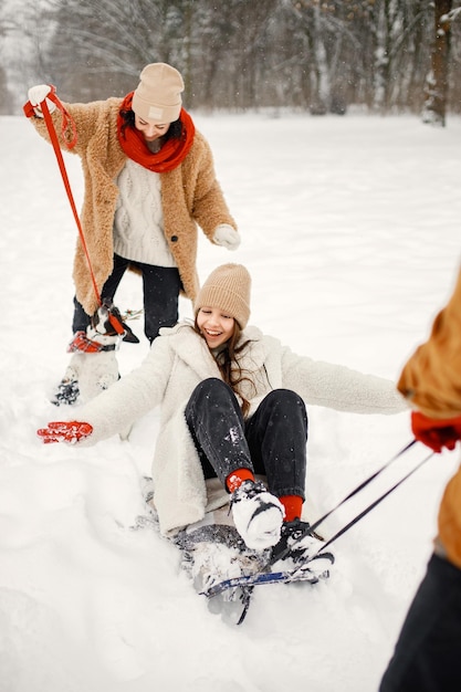 Teen siblings their mother and black dog riding a sled at winter park