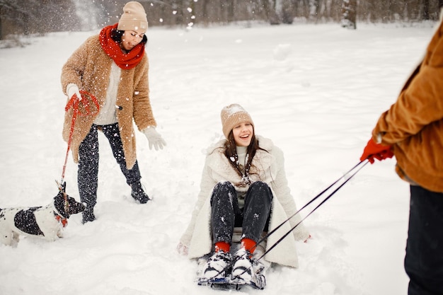 Teen siblings their mother and black dog riding a sled at winter park