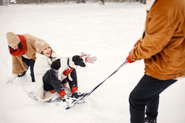 Teen siblings their mother and black dog riding a sled at winter park