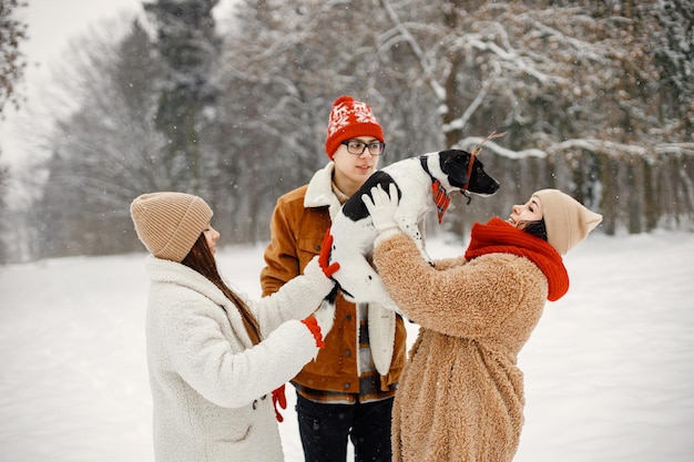 Teen siblings their mother and black dog standing at winter park