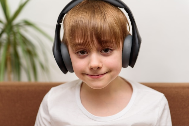 Teen sits in headphones and smiles. Guy listens to music.