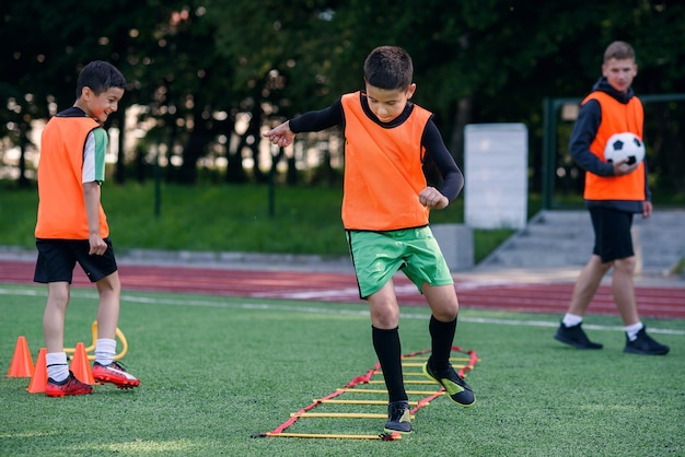Teen soccer players perform run exercises with overcoming obstacles