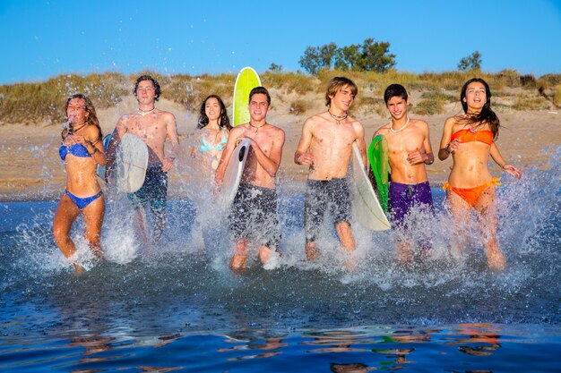 Photo teen surfers group running beach splashing