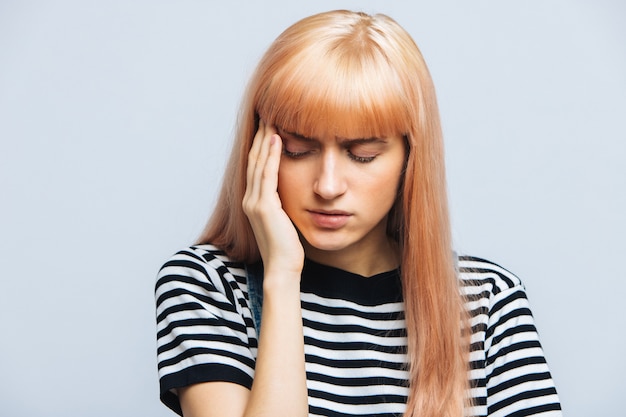 Подросток женщина, имеющая головную боль, держа ее висок, чувствуя давление