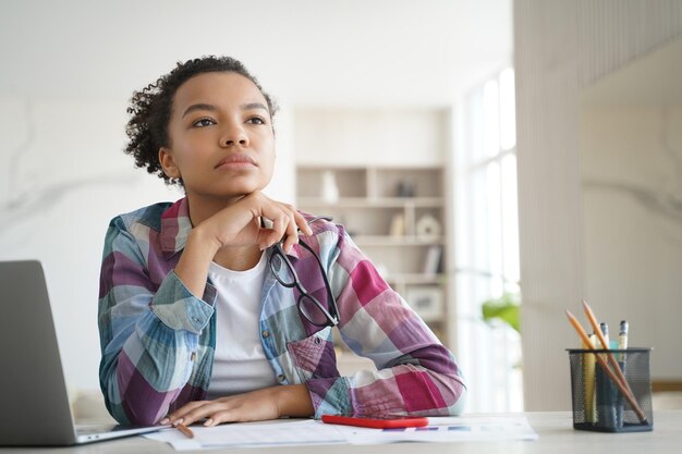 Photo teenage afro girl is bored at online lesson remote study at high school or college at home